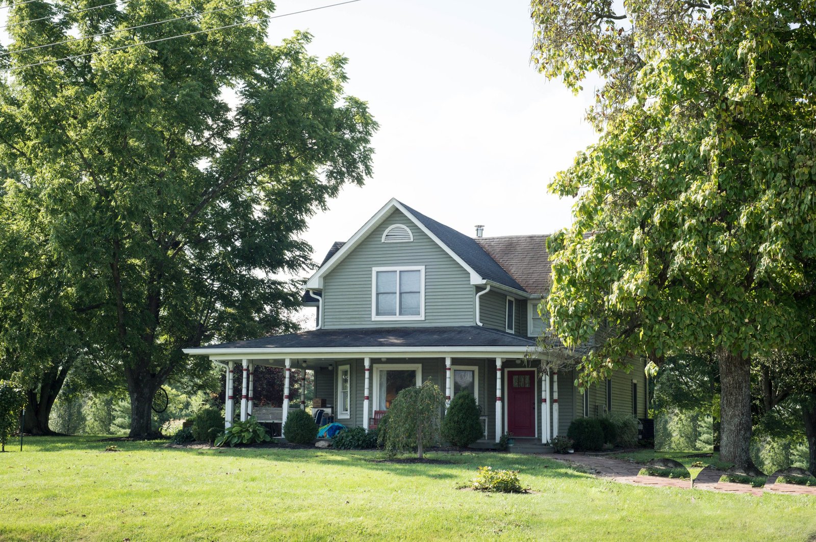 Photograph of green farmhouse with trees by New Albany artist Annie Dash Studios